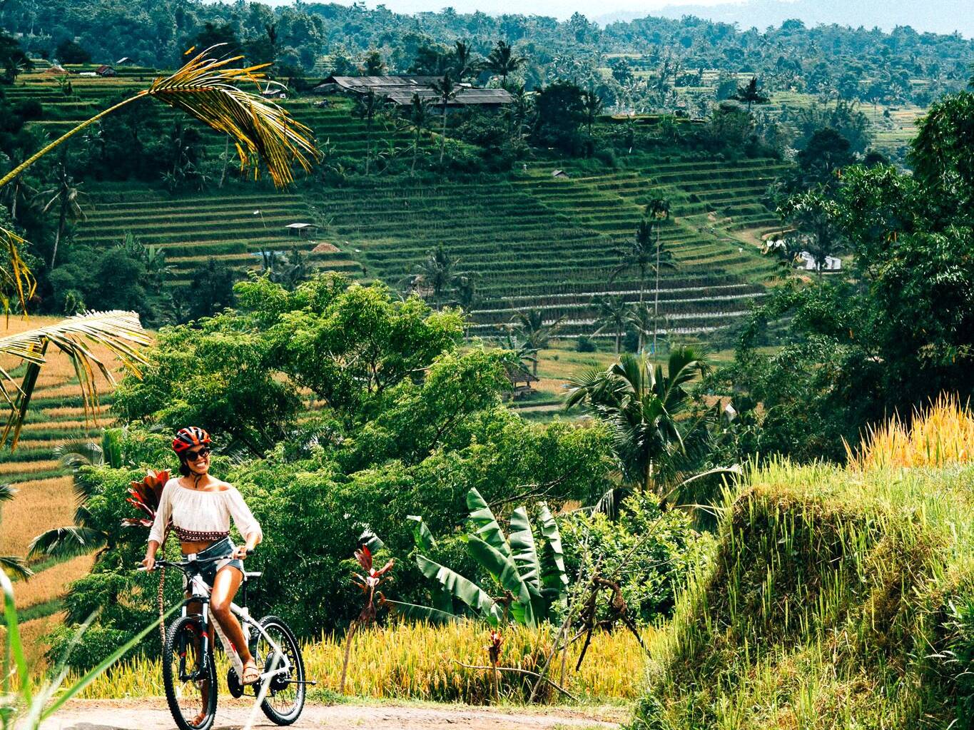 Female traveller on bicycle by rice fields in Bali